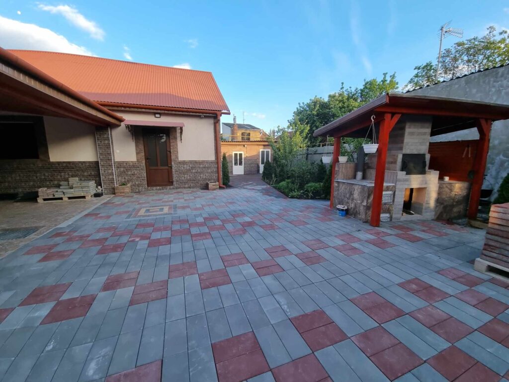 Detailní pohled na zámkovou dlažbu složenou do pravidelného vzoru na venkovní ploše.